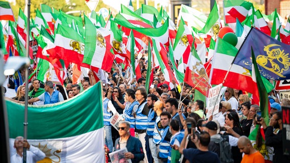 Demonstrierende halten Plakate und Fahnen anlässlich des Todestages von Jina Mahsa Amini im Iran. © picture alliance/dpa Foto: Jonas Walzberg