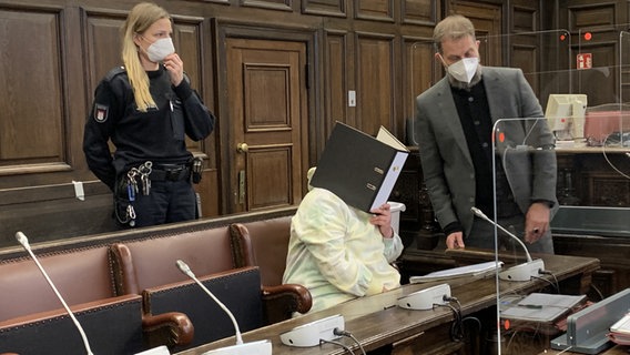 Eine IS-Rückkehrerin hält sich einen Aktenordner im Gerichtssaal vom Oberlandesgericht Hamburg vor das Gesicht. © NDR Foto: Elke Spanner