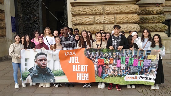 Joel aus Ghana steht mit Mitschülern vor dem Hamburger Rathaus hinter einem Plakat mit der Forderung "1, 2, 3, 4 - Joel bleibt hier!". © picture alliance / dpa Foto: Martin Fischer