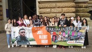 Joel aus Ghana steht mit Mitschülern vor dem Hamburger Rathaus hinter einem Plakat mit der Forderung "1, 2, 3, 4 - Joel bleibt hier!". © picture alliance / dpa Foto: Martin Fischer