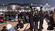 Polizisten stehen eine halbe Stunde vor dem Jahreswechsel am Jungfernstieg in der Menschenmenge. Die Polizei hat in Hamburg für den Jahreswechsel ein örtlich beschränktes Böllerverbot rund um die Binnenalster ausgesprochen. © picture alliance / dpa Foto: Jonas Walzberg