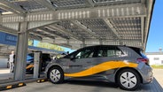 Ein Fahrzeug steht auf einem Parkplatz, der mit Solarzellen überdacht ist. © NDR / Reinhard Postelt Foto: Reinhard Postelt