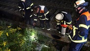 Mehrere Feuerwehrmänner begutachten einen Kabelschacht an Bahngleisen in Hamburg. © TV News Kontor 