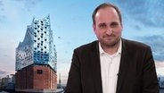 Daniel Kaiser im Studio von NDR 90,3 vor einem Elbphilharmonie-Hintergrund © NDR / Elbphilharmonie / Maxim Schulz 