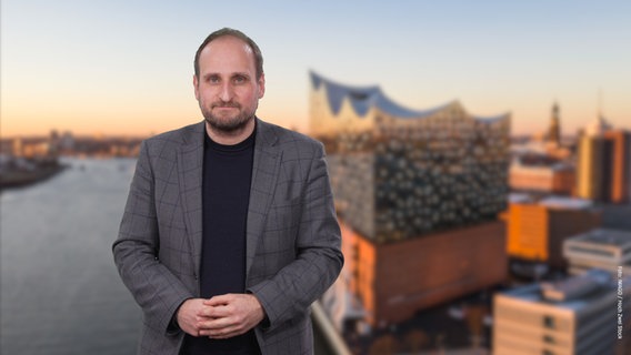 Daniel Kaiser steht vor einem Foto der Elbphilharmonie. © NDR 