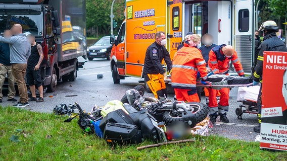 Nach einem Unfall in Hamburg liegt ein Motorrad auf dem Grünstreifen neben einer Straße. © Blaulicht-News 
