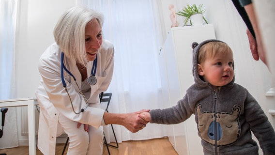 Eine Kinderärztin begrüßt ein Kind. © picture alliance / dpa Themendienst Foto: Christin Klose
