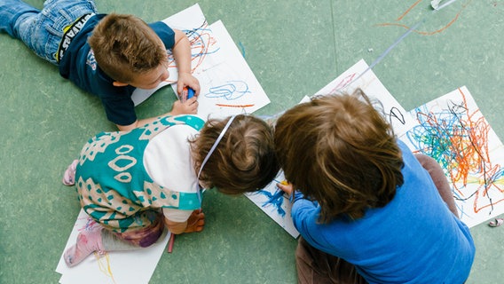 Kinder malen in Hamburg auf dem Boden einer Kindertagesstätte. © picture alliance/dpa Foto: Markus Scholz