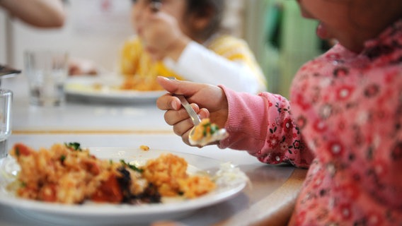 Ein Kind mit einem Löffel in der Hand beim Essen in einer Kindertagesstätte. © Angelika Warmuth/dpa Foto: Angelika Warmuth