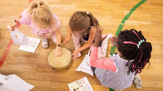 Drei Kita-Mädchen machen gemeinsam Musik. © dpa Foto: Christian Charisius