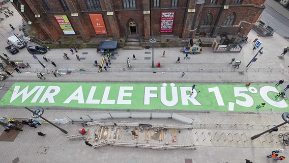 Aktivisten von Fridays for Future malen den Schriftzug "WIR ALLE FÜR 1,5 GRAD" auf die Mönckebergstraße. © picture alliance/dpa Foto: Georg Wendt