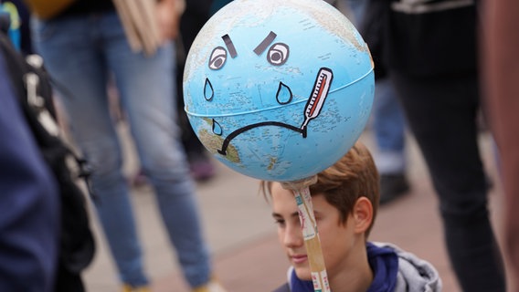 Bei einer Klimastreik-Demo in Hamburg hält ein Junge eine Erdkugel, die weint. © Marcus Brandt/dpa 