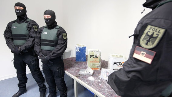 Zollbeamte stehen an einem Tisch im Zollfahndungsamt Hamburg, auf dem Kokain liegt. © picture alliance/dpa | Bodo Marks Foto: Bodo Marks