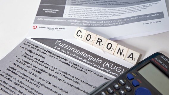 Ein Taschenrechner liegt neben Unterlagen für Kurzarbeitergeld. © picture alliance/Fotostand 