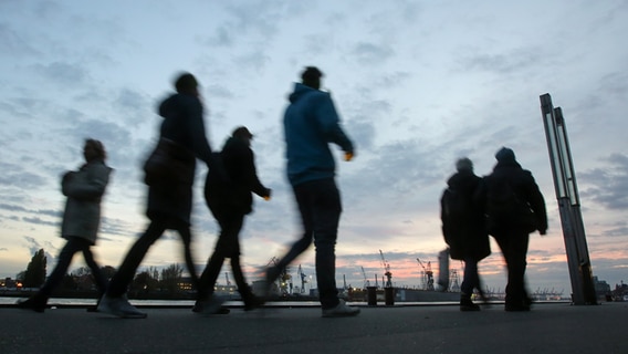 Passanten sind an den St. Pauli Landungsbrücken am Hamburger Hafen unterwegs. © picture alliance/Bodo Marks/dpa 