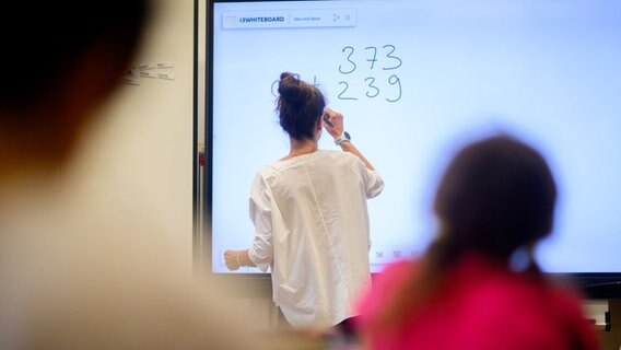 Eine Lehrerin schreibt eine Mathematikaufgabe auf eine digitale Schultafel. © picture alliance / dpa Foto: Julian Stratenschulte