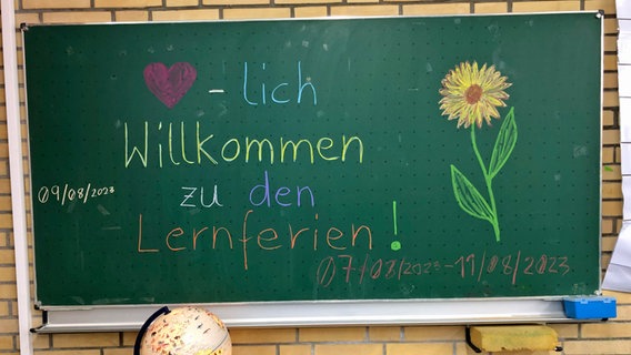 "Herzlich Willkommen zu den Lernferien" steht auf einer Tafel in einer Schule in Hamburg. © NDR Foto: Andreas Gartner