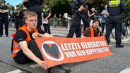Mehrere Personen der Gruppe "Letzte Generation" blockieren eine Straße in Hamburg. © NDR Foto: Finn Kessler