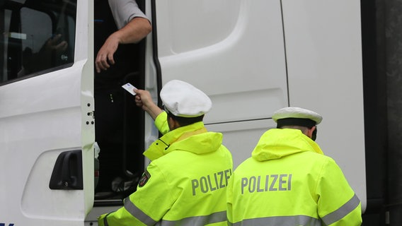 Polizisten kontrollieren einen Lkw-Fahrer. © dpa/picture-alliance Foto: Ina Fassbender