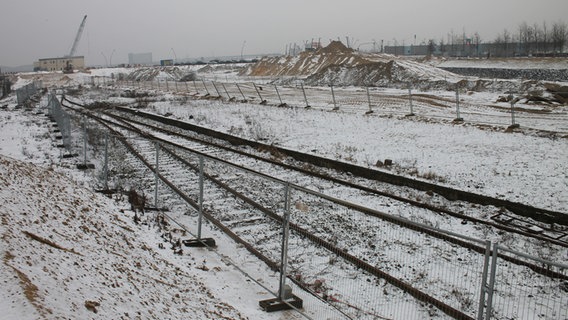 Ein von Gitterzäunen gerahmtes Stück Gleis mit Bahnsteig liegt vor Sandbergen in der Hafencity. © NDR Foto: Daniel Sprenger