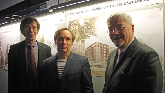 Oberbaudirektor Jörn Walter, Architekt Wolfgang Lorch und Hafencity-Geschäftsführer Jürgen Bruns-Berentelg (von links) vor dem Siegerentwurf für das Dokumentationszentrum. © NDR Foto: Daniel Sprenger