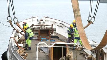 Das geborgene Schiff "No. 5 Elbe" wird mit Hilfe von Kränen angehoben. © NDR Foto: Screenshot