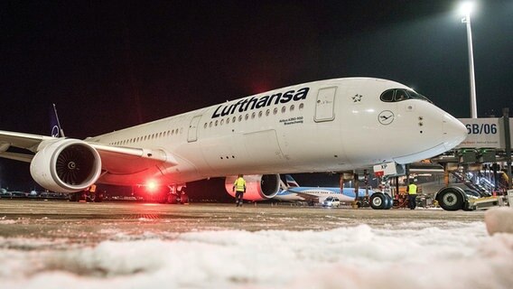 Der Airbus A350 der Lufthansa steht auf dem Rollfeld des Hamburger Flughafens. Im Vordergrund ist Schnee zu sehen. © dpa bildfunk Foto: Daniel Bockwoldt