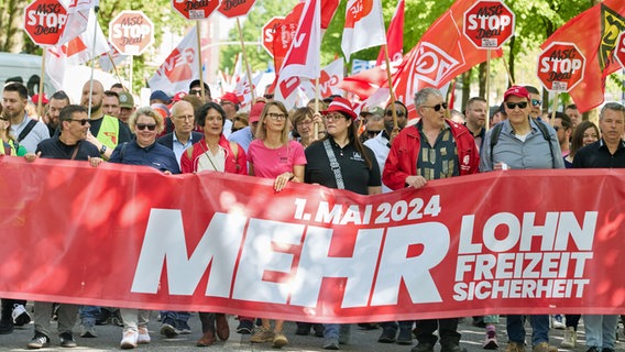 Demonstranten halten ein Transparent mit der Aufschrift "1.Mai 2024 Mehr Lohn, Freizeit, Sicherheit" in Hamburg-Altona. © picture alliance / dpa Foto: Georg Wendt