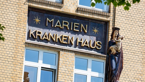 Eine Statute steht neben dem Schriftzug des Marienkrankenhauses im Hamburger Stadtteil Hohenfelde. © picture alliance Foto: Patrick Franck