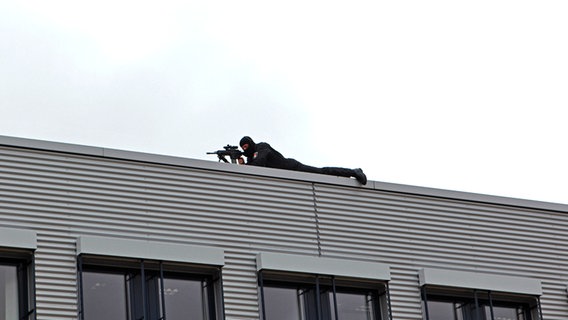 Ein Scharfschütze liegt auf einem Dach. © Carolin Fromm/NDR Foto: Carolin Fromm