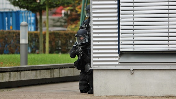 Zwei MEK-Beamte verstecken sich hinter einer Hausecke. © Carolin Fromm/NDR Foto: Carolin Fromm