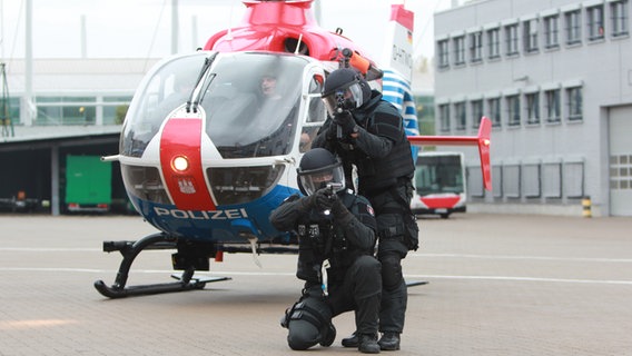 Zwei MEK-Beamte stehen vor einem Helikopter und zielen mit Gewehren in die Kamera. © Carolin Fromm/NDR Foto: Carolin Fromm