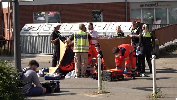 Zwei Opfer werden in Harburg von einem Notarzt versorgt werden. Polizisten sichern das Gebiet. © NonstopNews Foto: NonstopNews