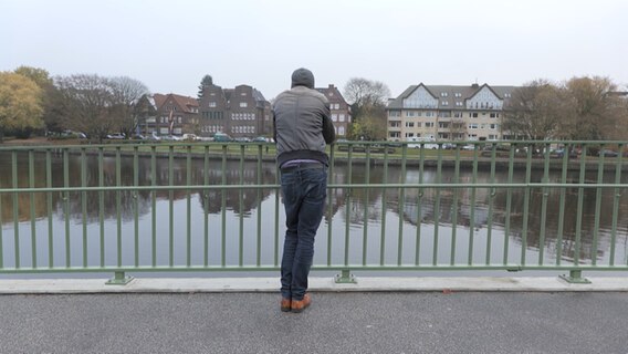 Eine Person steht an einer Uferzone und sieht in die Ferne. © NDR Foto: Screenshot