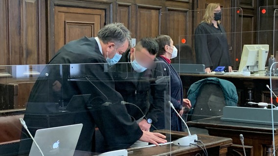Der Angeklagte und sein Anwalt lehnen sich im Gerichtssaal über den Tisch, sie sind im Gespräch. © NDR Foto: Elke Spanner