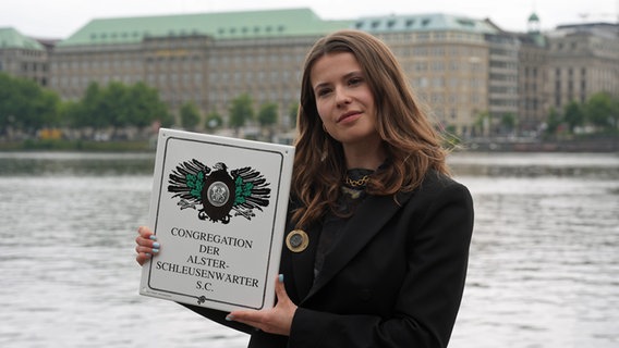 Klima-Aktivistin Luisa Neubauer steht nach der Auszeichnung zur Ehren-Alster-Schleusenwärterin an der Binnenalster und präsentiert ihre Auszeichnung © picture alliance / dpa Foto: Marcus Brandt