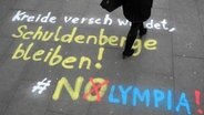 Eine Passantin geht am 24.11.2015 in Hamburg über einen Schriftzug "Kreide verschwindet, Schulnebgere bleiben!"  Foto: Aleksandra Bakmaz