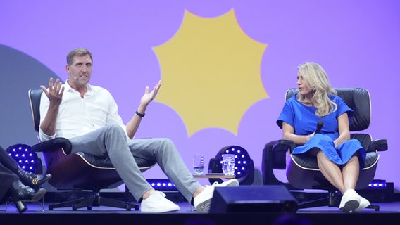 Dirk Nowitzki, ehemaliger NBA-Basketballprofi, sitzt neben seiner Schwester Silke auf der Bühne während der Digitalmesse OMR in den Hamburger Messehallen. © picture alliance / dpa Foto: Marcus Brandt