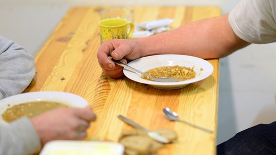 Zwei Personen essen in einer Einrichtung für obdachlose Menschen. © picture alliance / Maurizio Gambarini/dpa 