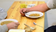 Zwei Personen essen in einer Einrichtung für obdachlose Menschen. © picture alliance / Maurizio Gambarini/dpa 