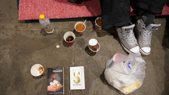 Füße und Kaffeebecher eines obdachlose Mannes von oben betrachtet an seinem Schlafplatz auf der Straße in der Hamburger Innenstadt. © picture alliance/dpa | Marcus Brandt Foto: Marcus Brandt