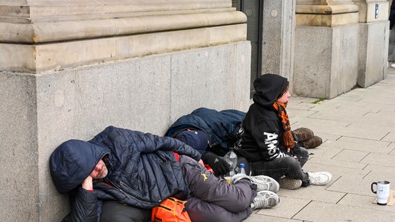 Zwei obdachlose Menschen liegen in Hamburg am Rand einer Straße. © picture alliance / Schoening | Schoening Foto: Schoening