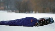 Ein Obdachloser liegt an der Hamburger Außenalster im Schnee. © dpa Foto: Kay Nietfeld