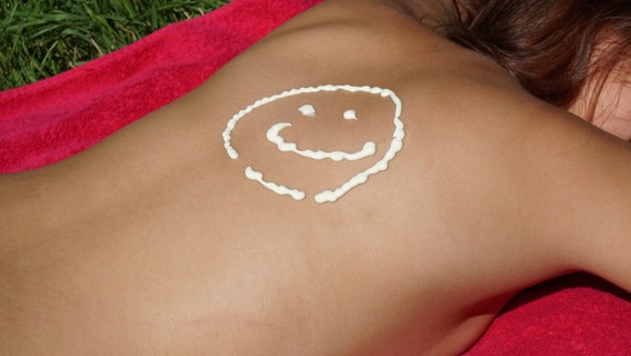 Auf den Rücken einer Frau ist mit Sonnencreme ein Smiley gemalt. © picture alliance/Zoonar/Axel Bueckert Foto: Axel Bueckert