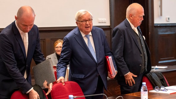 Der angeklagte Bankier Christian Olearius steht zwischen seinen Anwälten Bernd Schünemann (links) und Peter Gauweiler (rechts) im Gerichtssaal des Bonner Landgerichts. © dpa Foto: Thomas Banneyer