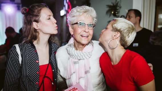 Eine ältere Dame bekommt von zwei jungen Frauen einen Kuss auf die Wange. © kukuun Foto: Jonas Krantz
