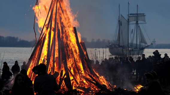 Schaulustige beobachten an der Elbe in Hamburg-Blankenese ein großes Feuer. © dpa-bildfunk Foto: Angelika Warmuth