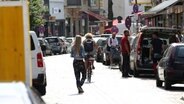 Eine Radfahrerin fährt durch die Bahrenfelder Straße in Ottensen, am Rand parken Autos. © Imago/Nikito 