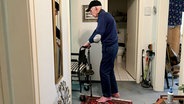 Rentner Horst Peinemann schiebt einen Pflegestuhl durch seine Wohnung. © NDR 