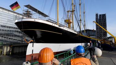 Das Segelschiff "Peking" liegt vor dem Ausdocken in der Peters Werft, Arbeiter stehen am Pier. Das Segelschiff "Peking" liegt vor dem Ausdocken in der Peters Werft, Arbeiter stehen am Pier. © picture alliance / dpa Foto: Carsten Rehder